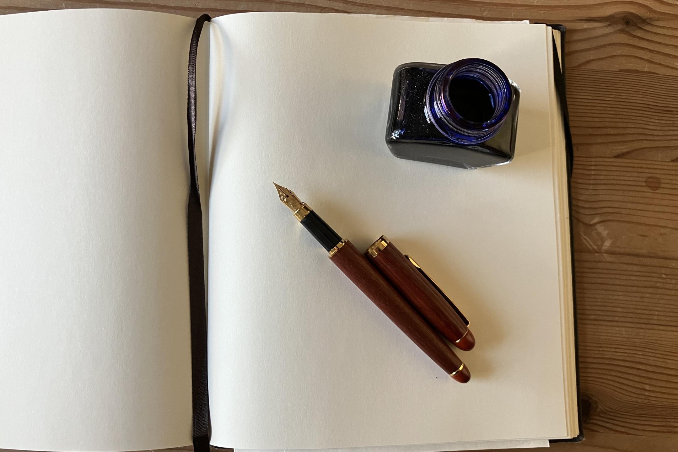 Leere Seite eines offenen Buches, Füllfederhalter, Tintenfass