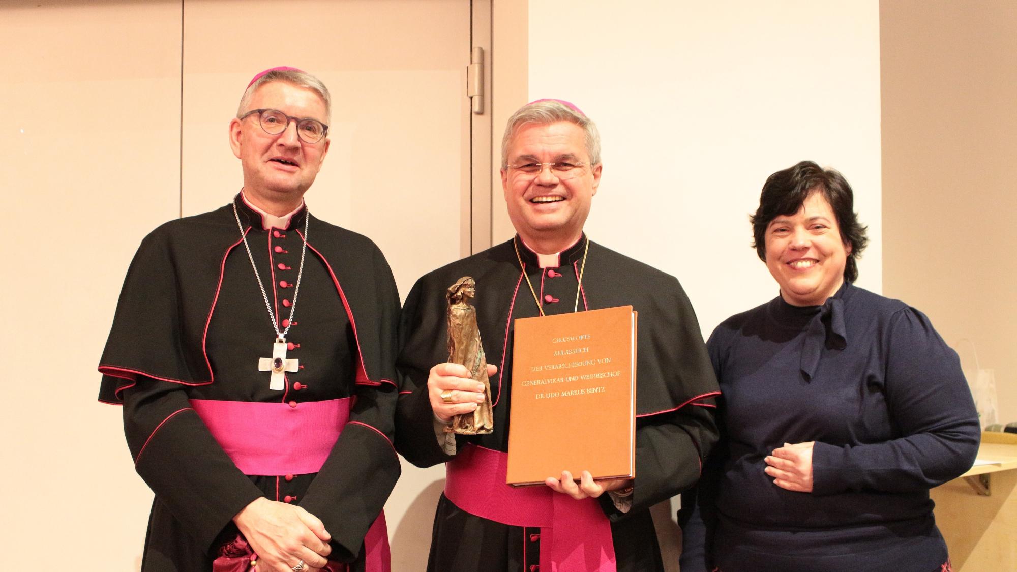 Mainz, 18. Februar 2024: Bischof Peter Kohlgraf überreichte gemeinsam mit Stephanie Rieth (rechts) die Geschenke des Bistums an den scheidenden Weihbischof Udo Markus Bentz (Mitte).