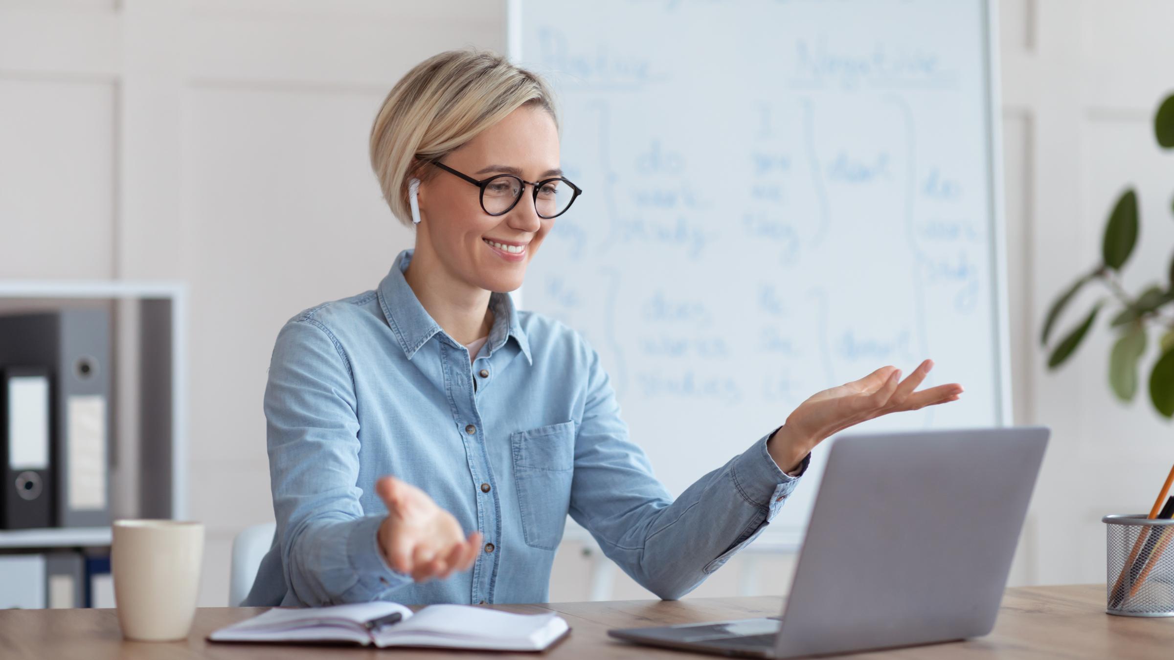 Experienced English teacher giving online lesson on laptop, chatting with students, participating in webinar from home