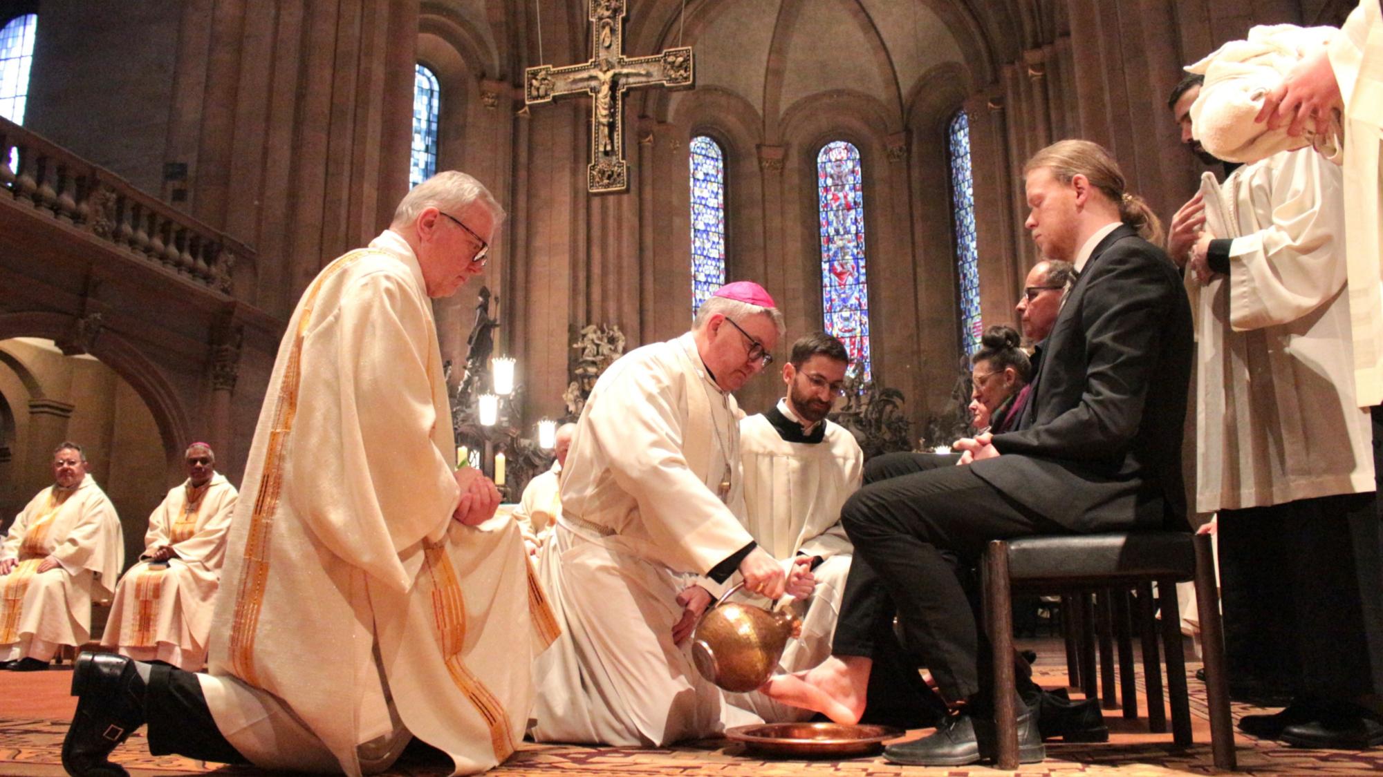 Mainz, 2. April 2026: Der Mainzer Bischof Peter Kohlgraf bei der Fußwaschung im Mainzer Dom; assistiert von Diakon Professor Helmut Pulte (links) und dem Mainzer Seminaristen Joseph Möller (rechts).